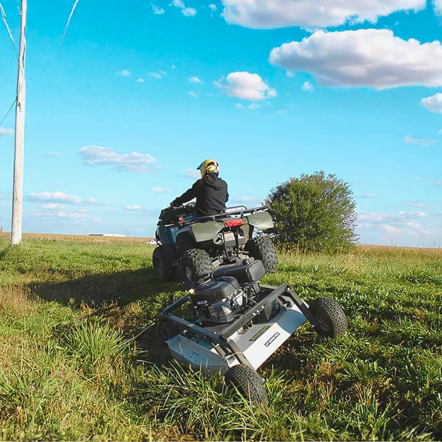 Person riding a Rough Cut Mower in a grassy field with a blue sky and clouds.
